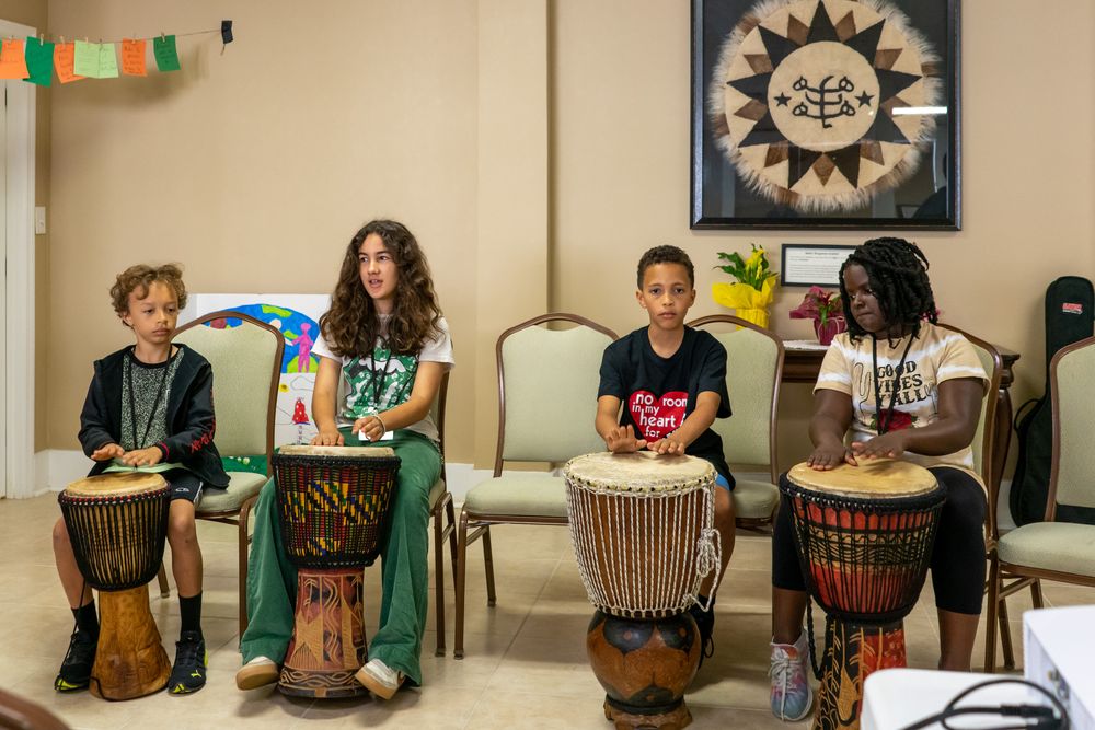 Four children perform on drums at a Baha'i gathering.